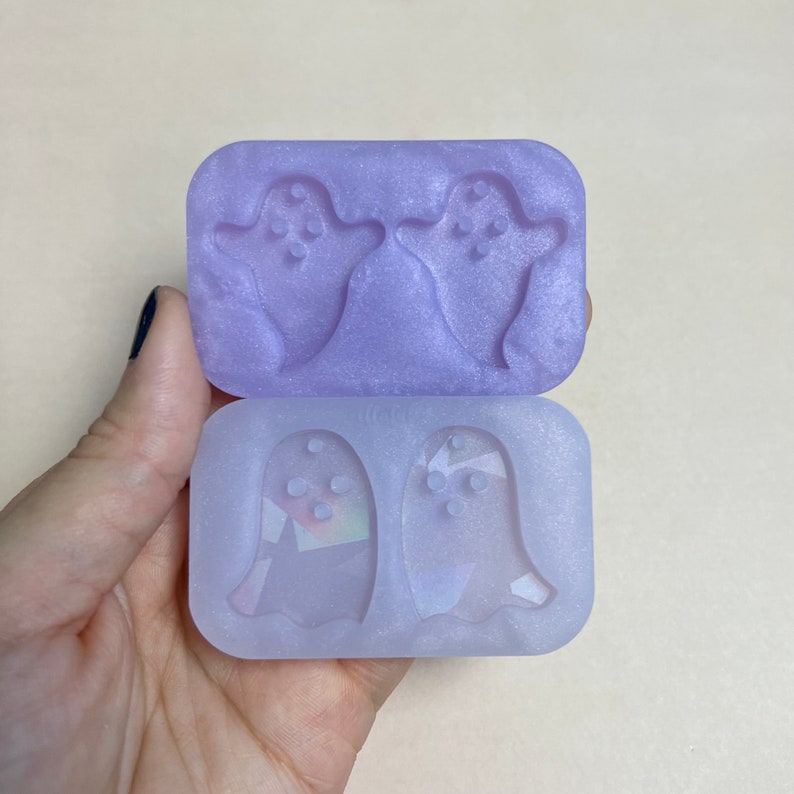 May include: A clear purple silicone mold with two ghost shapes. The mold is designed to create small, detailed ghost shapes.