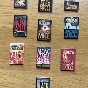 Op de afbeelding: Een verzameling miniatuur James Patterson boekomslagen, waaronder titels als "Kill Alex Cross" en "Double Cross". De omslagen tonen verschillende kleuren en ontwerpen, met de naam van de auteur prominent weergegeven.
