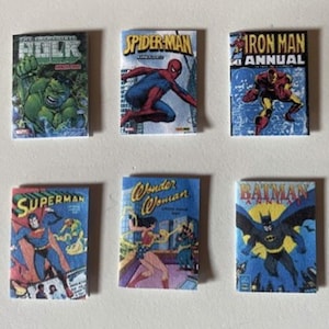 May include: A set of six miniature comic books featuring Marvel and DC characters. The covers display The Incredible Hulk, Spider-Man, Iron Man Annual, Superman, Wonder Woman, and Batman Annual with their respective colourful graphic illustrations.