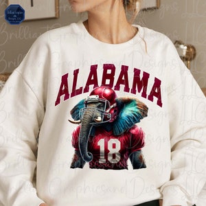 May include: White sweatshirt with a red and blue graphic of an elephant wearing a football helmet and jersey with the word "ALABAMA" and the number "18" on it.