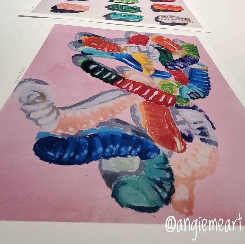 May include: A colorful abstract painting of gummy worms on a pink background. The painting is done in a loose, expressive style, with vibrant colors and bold brushstrokes. The gummy worms are arranged in a chaotic, yet pleasing, composition. The painting is signed "@angiemeart" in the lower right corner.