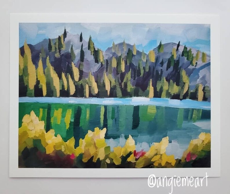 May include: A painting depicting a lake scene with a mountain range in the background. The lake is a bright blue-green colour and the mountains are a dark purple-grey. There are yellow flowers in the foreground.