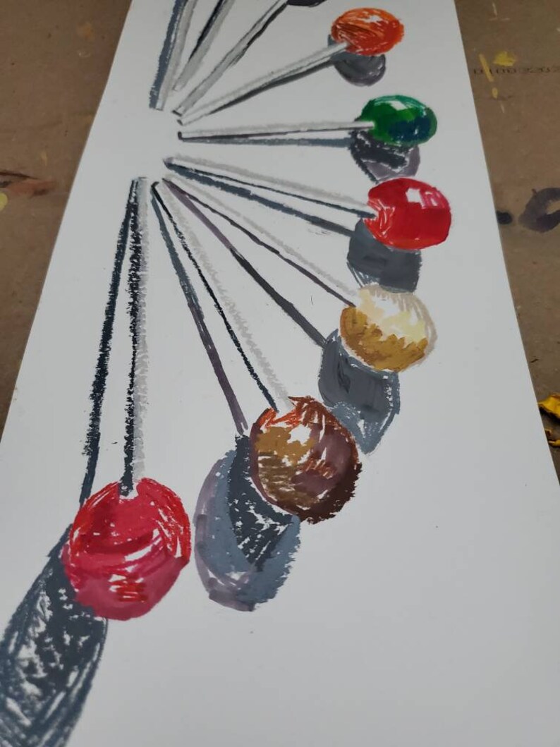 May include: A set of 10 colorful round lollipops on sticks arranged in a circle. The lollipops are red, orange, green, yellow, brown, and white.