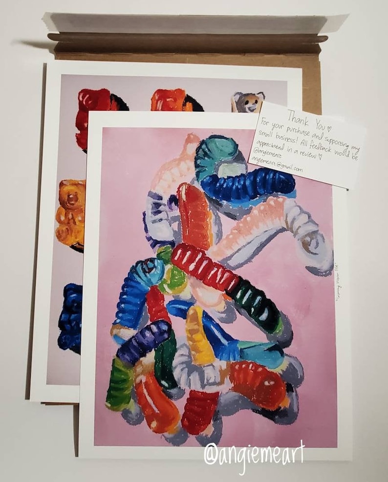 May include: A painting of a pile of colorful gummy worms on a pink background. The gummy worms are arranged in a random pattern and are of different shapes and sizes. The painting is signed "@angiemeart" in the bottom right corner.