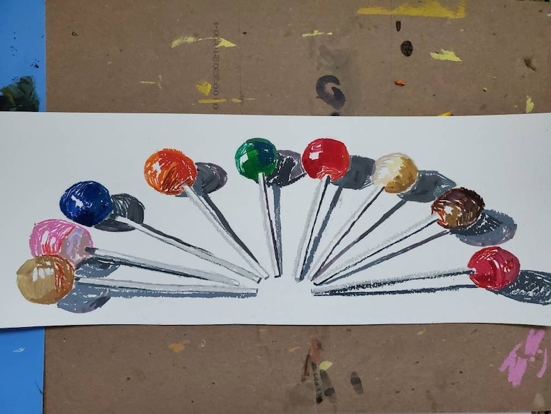 May include: A collection of 10 colorful lollipops arranged in a semi-circle on a white background. The lollipops are on sticks and have a variety of colors, including red, blue, green, orange, pink, and brown.