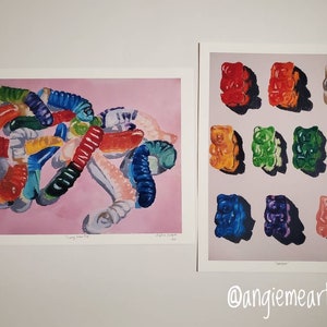 May include: Two watercolor paintings of gummy candies. The first painting shows a pile of colorful gummy worms on a pink background. The second painting shows nine gummy bears in different colors arranged in a grid on a light gray background.