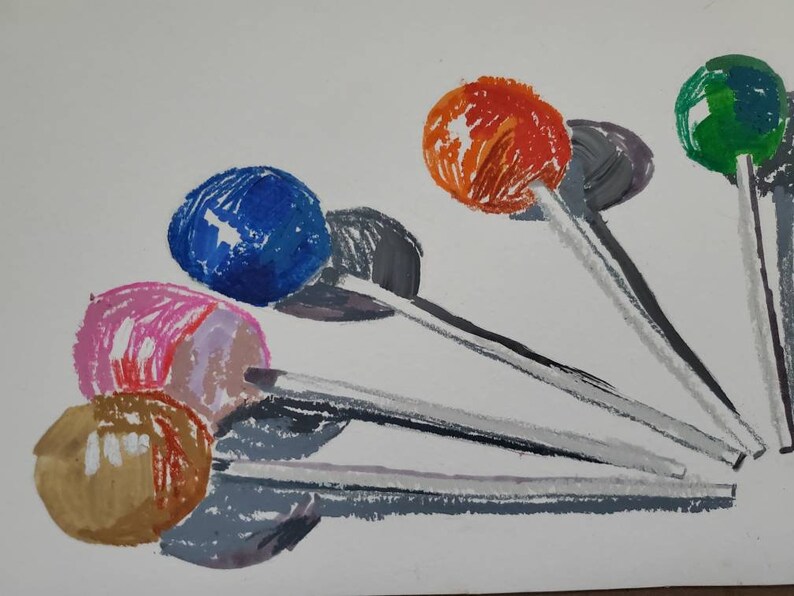 May include: A watercolor painting of six lollipops with different colored candy heads and white sticks. The lollipops are arranged in a fan shape with the candy heads facing the viewer. The colors of the candy heads are blue, pink, brown, orange, green, and gray.