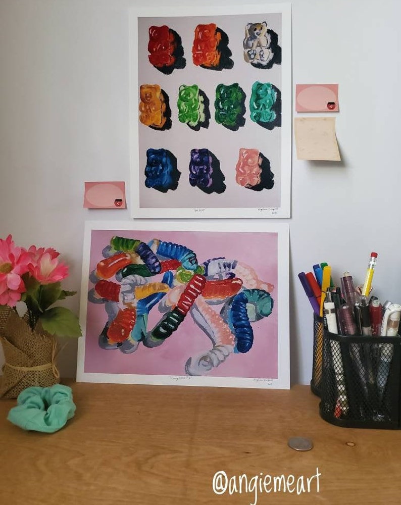May include: Two framed prints of gummy bear paintings. The top print features a grid of nine gummy bears in different colors. The bottom print features a pile of gummy worms in various colors and shapes.