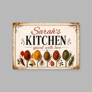 May include: A rectangular metal sign with a distressed cream background featuring the text Sarah's KITCHEN spiced with love. The design includes five silver spoons filled with various colourful spices, a red chilli pepper, and green herbs.