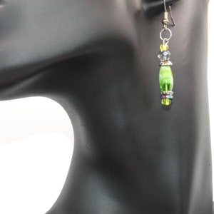 May include: Green glass bead dangle earrings with silver accents and a clear crystal bead.
