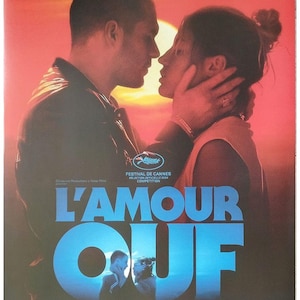 May include: Movie poster for "L'Amour Ouf" featuring a couple in a close embrace, with the title in large blue letters. The poster includes the Cannes Film Festival logo and credits.