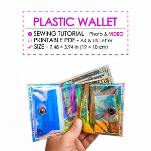May include: A clear, iridescent plastic wallet with a snap closure, holding cash and a credit card. The wallet is open, displaying its contents. The text "PLASTIC WALLET" is at the top, along with size details: 7.48 x 3.94 in (19 x 10 cm).
