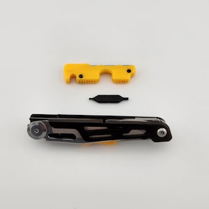 May include: A black multi-tool with a yellow handle and a black metal attachment. The multi-tool has a variety of tools, including a knife, a screwdriver, and a bottle opener.