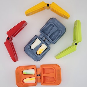 May include: An assortment of colorful earplug cases and earplugs. The cases are in red, yellow, green, orange, and gray. The earplugs are white and yellow. The cases are open and closed, showing the earplugs inside. The cases are labeled with "L" and "R".