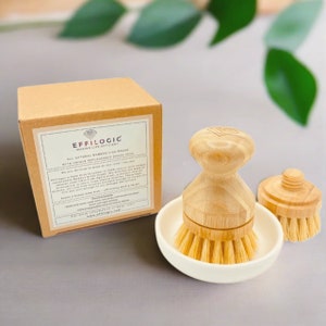 May include: A white ceramic dish with a bamboo dish brush with replaceable brush head. The dish brush is in a white ceramic dish with a smaller bamboo brush head. The box for the dish brush is brown with white text that reads "EFFILOGIC MAKING LIFE EFFICIENT ALL NATURAL BAMBOO DISH BRUSH WITH UNIQUE REPLACEABLE BRUSH HEAD We are thrilled to present to you our new EFFILOGIC Palm Dish Scrubber. That is eco-friendly, replaceable brush head is made from 100% natural Bamboo. The brush head is soft enough to remove food from delicate surfaces with high abrasive strength from aged bamboo. The brush head is designed to be easily replaceable with a twist and a turn. Care & Basic wash dish - wash with warm water and dish soap. - rinse with water and allow to air dry. - wrap with a bamboo cloth to prevent mold from forming. - for more information, help, and assistance visit www.effilogic.com.  "