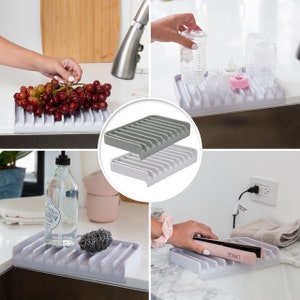 K&ouml;nnte beinhalten: Ein Satz aus vier grauen und wei&szlig;en Abtropfgestellen. Die Abtropfgestelle sind aus einem strapazierf&auml;higen, flexiblen Material gefertigt und f&uuml;r verschiedene K&uuml;chensp&uuml;len geeignet. Die Abtropfgestelle sind in verschiedenen Konfigurationen dargestellt, wobei ein Abtropfgestell eine Vielzahl von Gegenst&auml;nden enth&auml;lt, darunter eine Seifenflasche, ein Haargl&auml;tter und eine Traube.