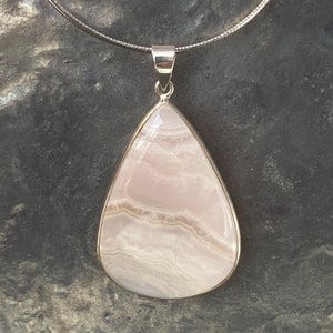 May include: A teardrop-shaped pendant made of white and pink agate with a silver chain.