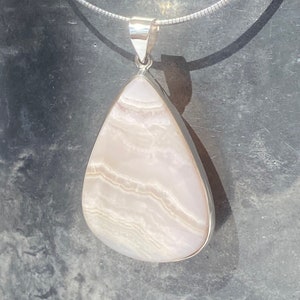 May include: A teardrop-shaped pendant with a white and pink agate stone set in sterling silver.