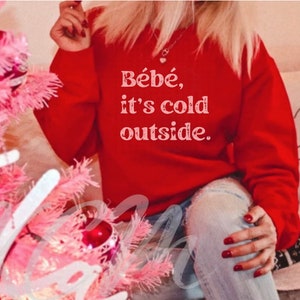 May include: Red sweatshirt with the text "Bébé, it's cold outside." in white.