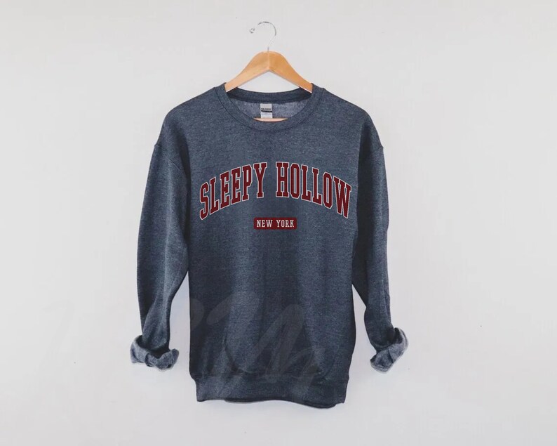 Może przedstawiać: Szara bluza z nadrukiem "SLEEPY HOLLOW NEW YORK" w kolorze bordowym.