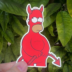 Puede incluir: Un diablo de dibujos animados rojo con cuernos y cola sosteniendo un tenedor. El diablo lleva un traje rojo y tiene una cara amarilla con un bigote negro. El fondo es una planta verde frondosa.