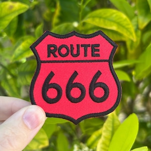 May include: Red and black embroidered patch shaped like a highway sign with the text "ROUTE 666" on it.