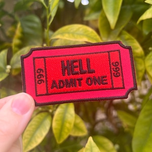 May include: Red ticket-shaped patch with black stitching and the text "HELL ADMIT ONE" and the numbers "666" on either side.
