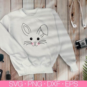May include: White sweatshirt with a black and white outline of a bunny rabbit face with pink cheeks. The bunny has a small bow on its head.