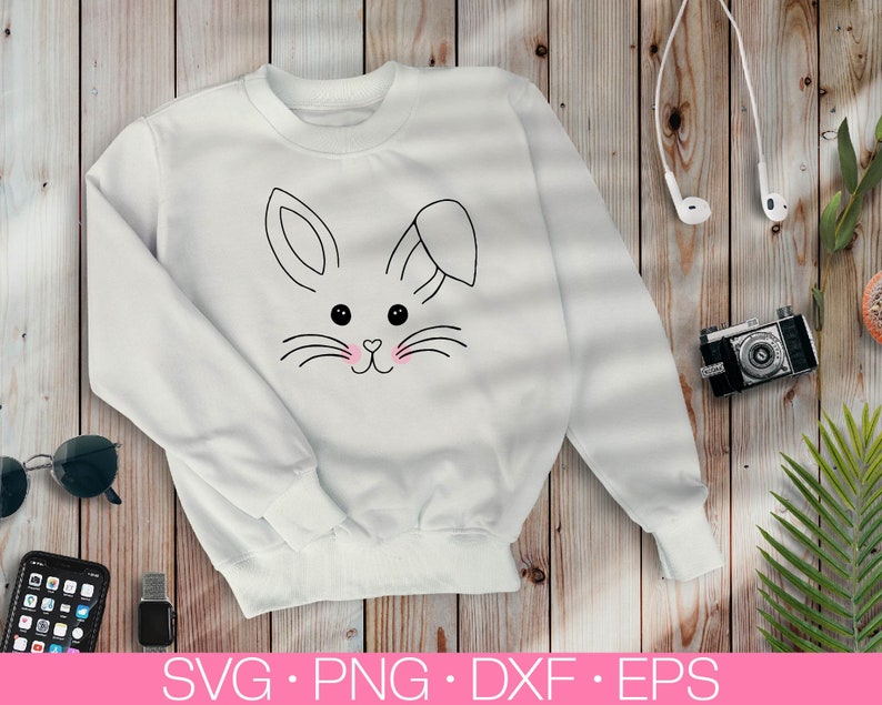 May include: White sweatshirt with a black and white outline of a bunny rabbit face with pink cheeks. The bunny has a small bow on its head.