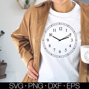 May include: A white t-shirt with a black clock design on the front. The clock face has black hands and black numbers.