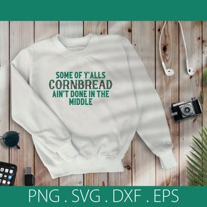 Puede incluir: Sudadera blanca con texto verde que dice "Some of y'all's cornbread ain't done in the middle."