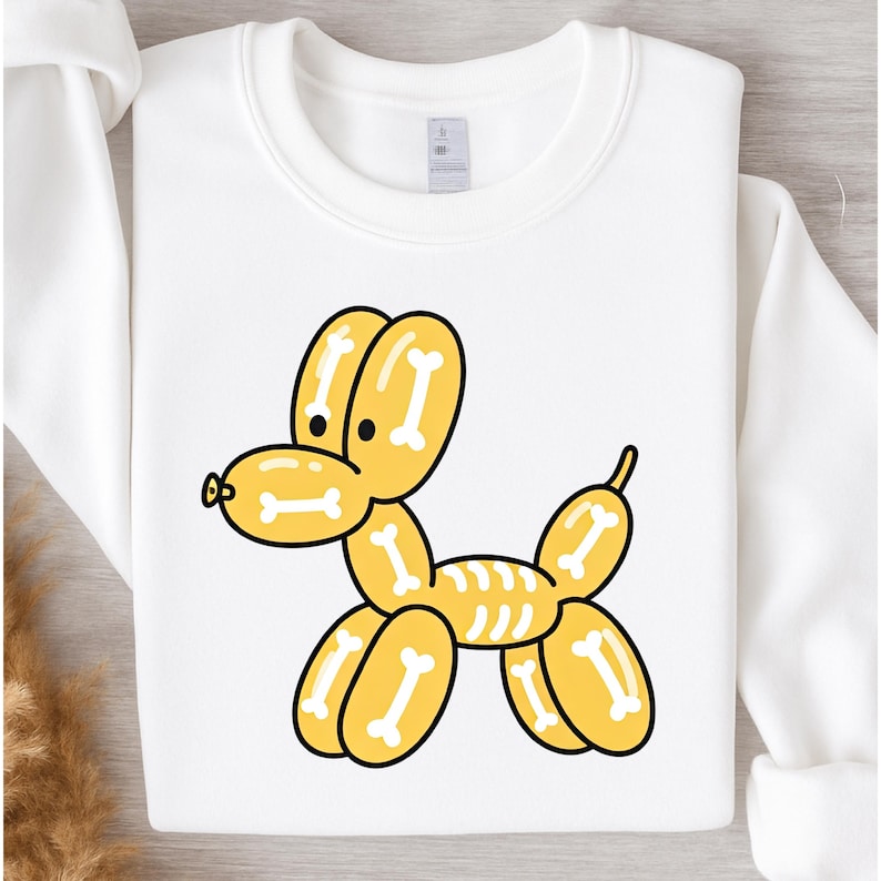 May include: White sweatshirt featuring a yellow balloon dog design with bone details. The cartoon dog has a black outline and is centered on the front of the long-sleeved top. The sweatshirt is made of a soft material.