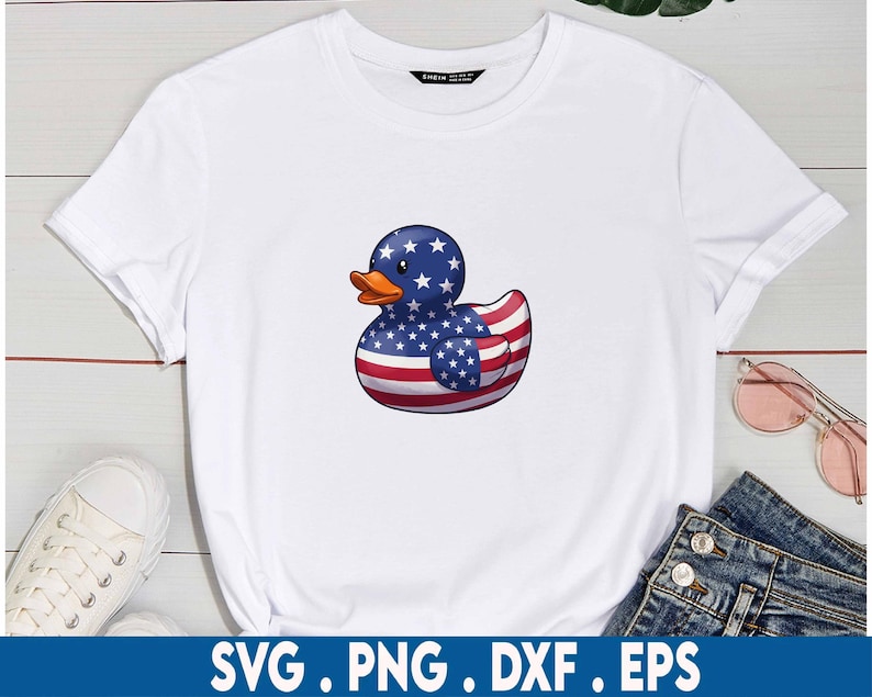 Puede incluir: Una camiseta blanca con un dise&ntilde;o de pato de goma. El pato est&aacute; decorado con la bandera estadounidense.