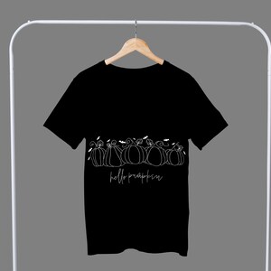 May include: Black t-shirt with a white graphic of pumpkins and the text "hello pumpkin".