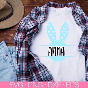 May include: A white t-shirt with a blue bunny ear design and the name "Anna" written in black text inside a circle.