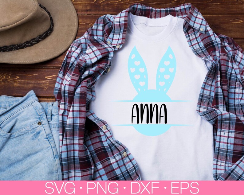 May include: A white t-shirt with a blue bunny ear design and the name "Anna" written in black text inside a circle.