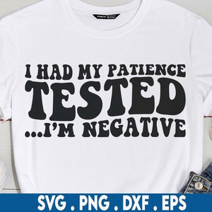 Könnte beinhalten: Weißes T-Shirt mit schwarzem Text, der "Ich hatte meine Geduld auf die Probe gestellt... Ich bin negativ" lautet.