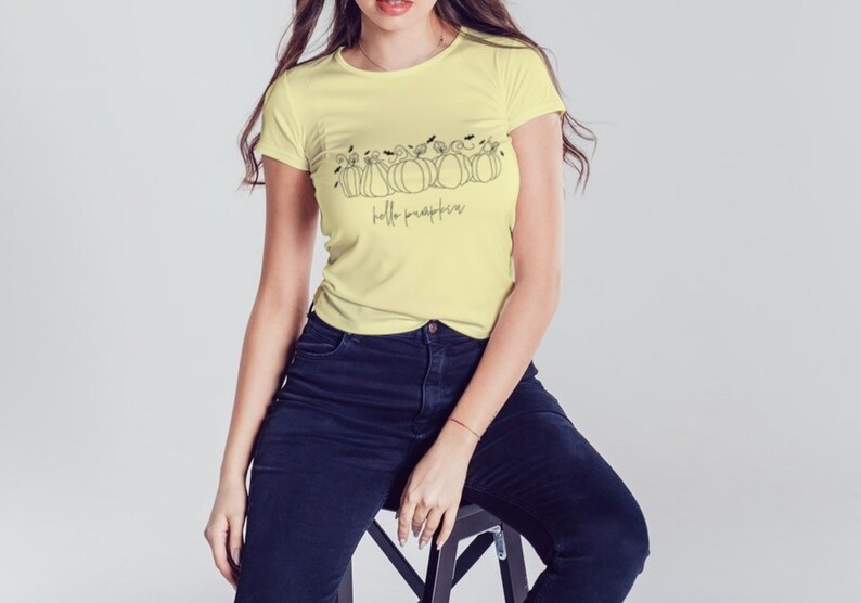 May include: A yellow t-shirt with a black line drawing of pumpkins and the text "hello pumpkin" on the front.