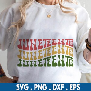 May include: A white sweatshirt with the word "Juneteenth" written three times in a retro, wavy font. The text is in red, yellow, and green.
