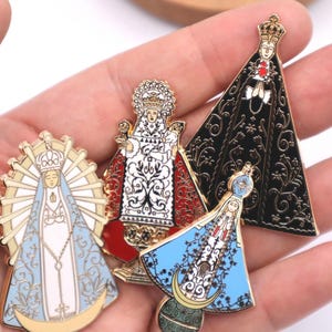 May include: Four enamel pins featuring religious figures. The pins are gold-toned and feature colorful designs. The figures are dressed in elaborate robes and have halos. The pins are perfect for adding a touch of faith to your clothing or bag.