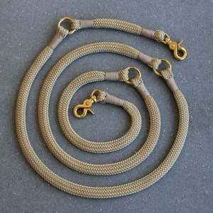 May include: Three beige rope dog leads with gold metal fittings. The leads are coiled together in a circular pattern.