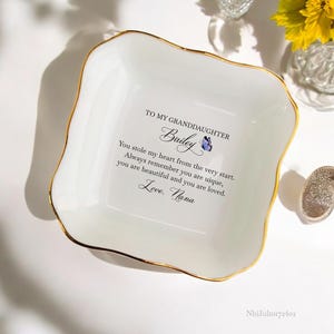 Puede incluir: Plato de cer&aacute;mica blanca para joyas con borde dorado. El plato tiene un mensaje que dice: "A mi nieta Bailey Me robaste el coraz&oacute;n desde el principio. Recuerda siempre que eres &uacute;nica, eres hermosa y eres amada. Con amor. Abuela"
