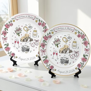 May include: Two white ceramic plates featuring a floral rose border, a banner with the text Nikolina & Dylan, and illustrations of wedding rings, a bouquet, a dog, a cat, champagne glasses, a camera, and hearts with initials J and B, dated August 29, 2026.