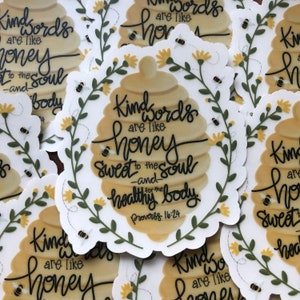 May include: A set of honeybee-themed stickers with the quote "Kind words are like honey, sweet to the soul -and- healthy for the body. Proverbs 16:24". The stickers feature a honeycomb design with yellow and green floral accents.