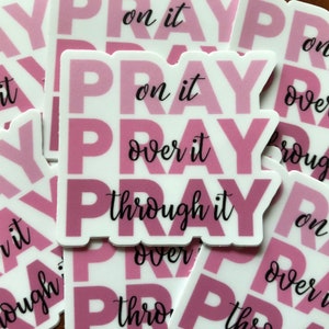 May include: Pink and white sticker with the text "Pray on it, Pray over it, Pray through it" repeated in a stacked design.