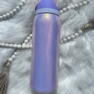 Op de afbeelding: Een herbruikbare waterfles in paars en wit met een roze deksel en het woord "avolo" gedrukt op de zijkant.