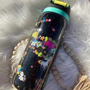 May include: Black water bottle with a glittery finish, decorated with colorful 80s-themed graphics. The design includes a unicorn, Pac-Man characters, and the text "80s". The bottle has a teal and yellow lid.
