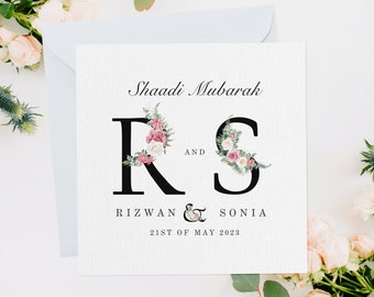 Puede incluir: Una invitación de boda con un diseño floral que presenta las letras "R" y "S" con el texto "Shaadi Mubarak" y "Rizwan & Sonia 21st of May 2023".