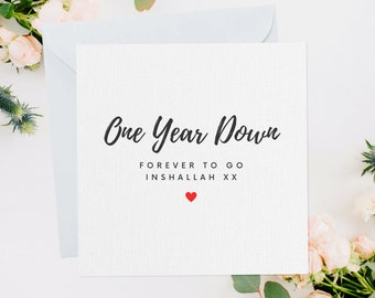 Könnte beinhalten: Eine weiße Karte mit schwarzem Text, der "One Year Down Forever To Go Inshallah XX" lautet, mit einem kleinen roten Herzen unter dem Text.