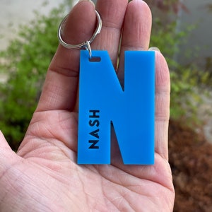 May include: A blue acrylic keychain with the letter N and the word NASH printed vertically on the left side.